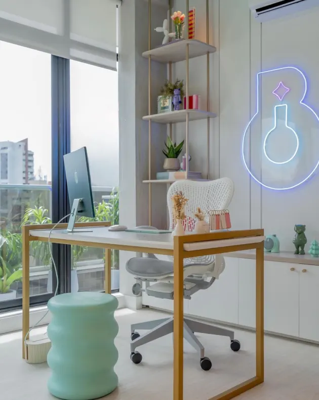 Mesa de trabalho do escritório da Branding Lab com o símbolo da marca em neon
